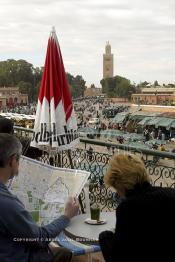 Image du Maroc Professionnelle de  Quelques touristes sont  installés avec leur verre de thé à la menthe sur la terrasse de l'hôtel café de France, la vue donnant sur la fameuse place Jemaa El Fana de Marrakech, Dimanche 27 Février 2005, au fond le minaret de la Koutoubia. (Photo / Abdeljalil Bounhar)